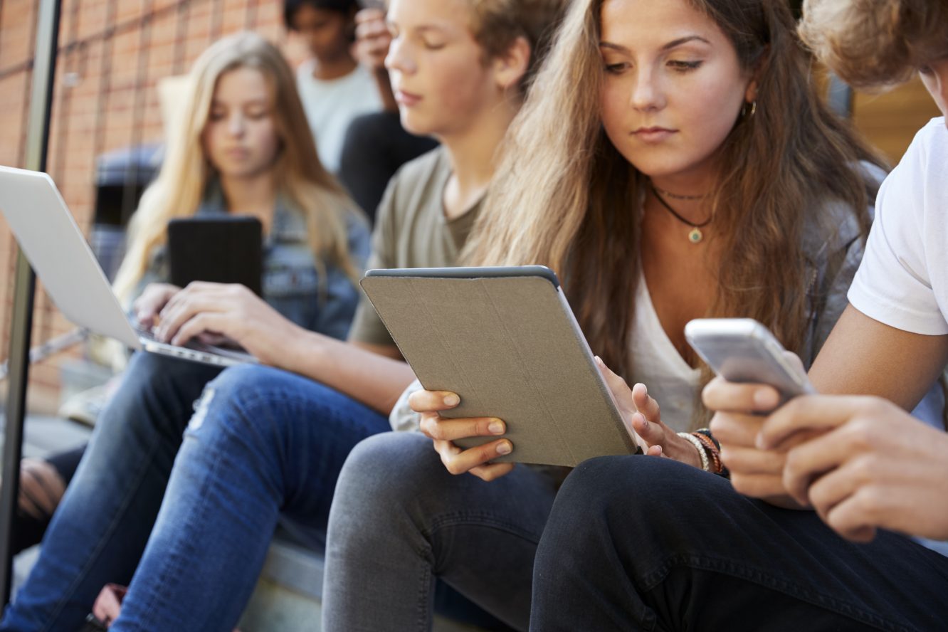 Teenage Students Using Digital Devices On College Campus