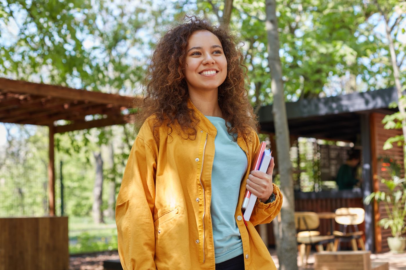 Student on a cafe terrace, holding textbooks